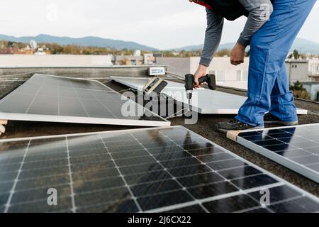 Man worker installing solar photovoltaic panel system using screwdriver. Alternative energy concept Stock Photo
