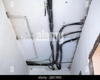 Electrical wiring on concrete ceiling. Repair the apartment without finishing. Electric cables Stock Photo