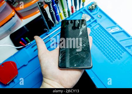 a broken mobile phone screen in the master's hand. Stock Photo