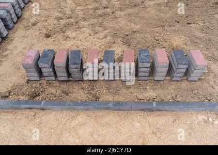 Laying of gray concrete paving slabs in the house courtyard driveway patio. Professional working masons install new tiles or slabs for the driveway, s Stock Photo