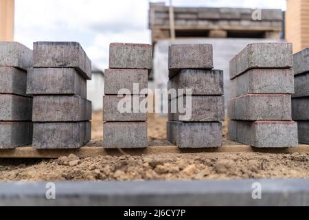 Laying of gray concrete paving slabs in the house courtyard driveway patio. Professional working masons install new tiles or slabs for the driveway, s Stock Photo