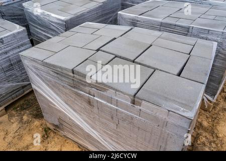 Laying of gray concrete paving slabs in the house courtyard driveway patio. Professional working masons install new tiles or slabs for the driveway, s Stock Photo