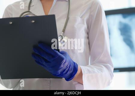 Radiologist checks x-ray image and holds clipboard in hands Stock Photo