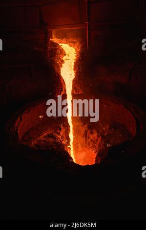 A stream of molten slag is poured into a metallurgical ladle Stock Photo