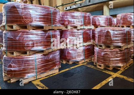 Coils of copper wire on wooden pallets in plant warehouse Stock Photo