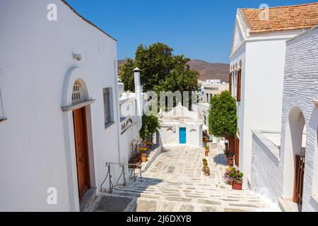 For the islands of the Cyclades archipelago typical narrow streets with white houses and blue roofs. Marble paved sidewalks. Located in the aegean sea Stock Photo