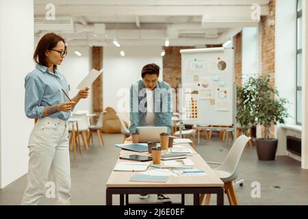 Two colleagues standing in the office and focused on work Stock Photo