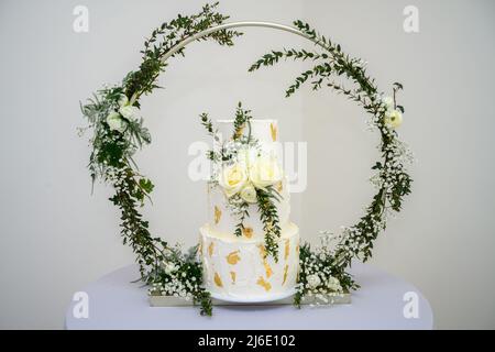 Three tier wedding cake with gold leaf and fresh flowers Stock Photo