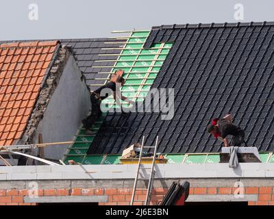 Sint Gillis Waas, Belgium, April 28, 2022, roofers put dark roof tiles on a house Stock Photo