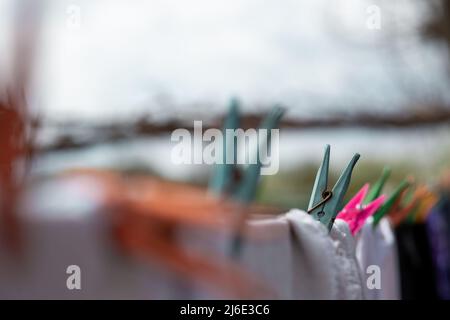 Linen dries on a rope, attached with multi-colored clothespins Stock Photo