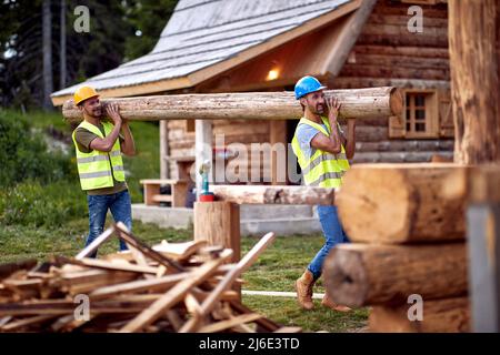 Teamwork .Smiling carpenters holds wooden planks on construction site Stock Photo