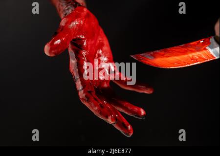Man holding knife with bloody hand on black background.  Stock Photo