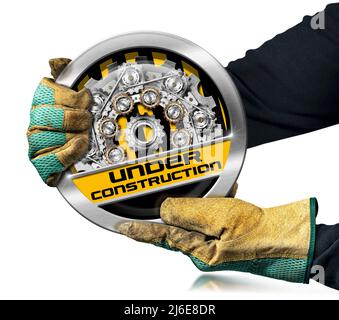 Gloved hands holding an under construction sign with metal cogwheels (gears), isolated on white background.