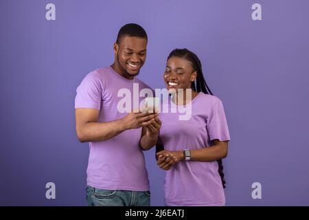Portrait of smiling black couple using smartphone Stock Photo