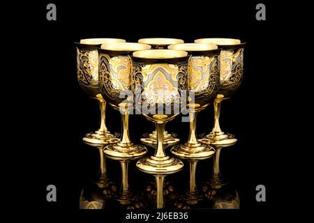 Six Golden Antique Vintage Brass Shot Glass Gilded on black background. metal Wine Cup goblet with Carving Engraving pattern. Stock Photo