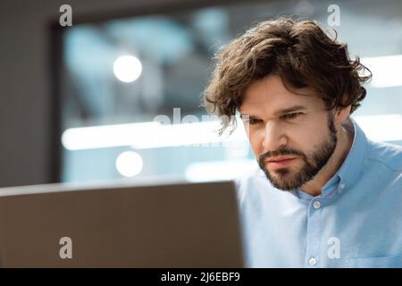Confused guy using laptop looking at screen Stock Photo