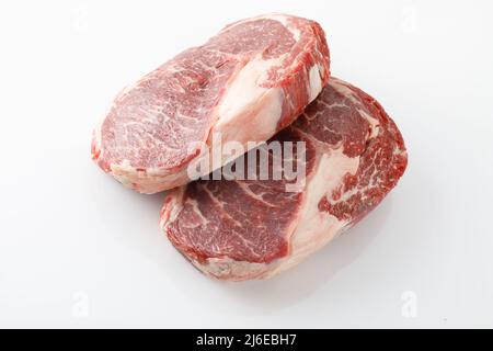 Two freshly cut boneless ribeye steaks on white butcher table Stock Photo