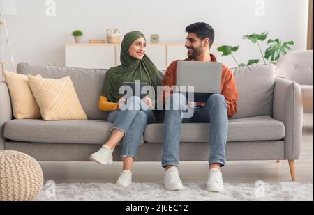 Middle Eastern Couple Using Laptop Computer And Tablet At Home Stock Photo