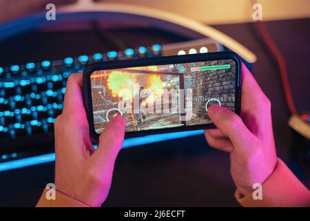 Hands of gamer playing mobile video games on his smartphone Stock Photo