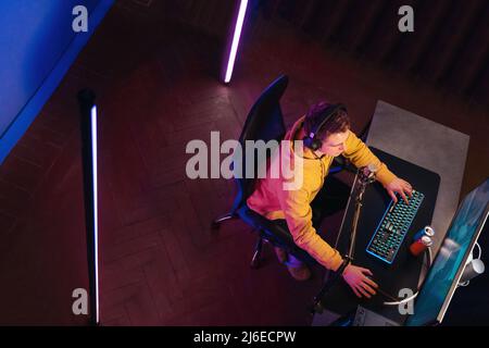 Top view of cyber sportsman playing computer game at home in neon color Stock Photo