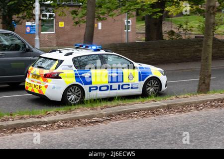West Yorkshire police car on Harehills Lane, Chapel Allerton, responding to an emergency with blue lights flashing, Leeds, England, UK Stock Photo