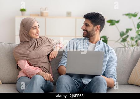 Happy Islamic Spouses Using Laptop Computer Together At Home Stock Photo