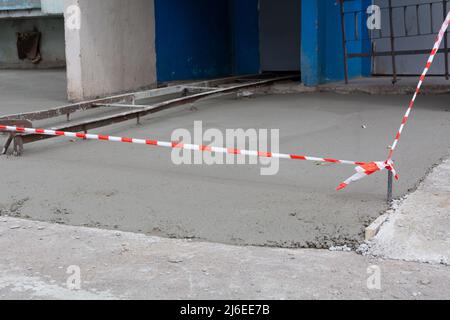 Blind area around the house. Construction of formwork for the blind area of the house. Construction tape around the cement pavement Stock Photo