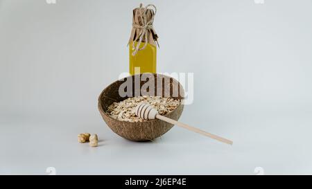 Oat flakes in bamboo bowl and honey with wooden stick on a white background with nuts. Stock Photo