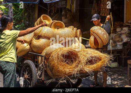 Young Vietnames man helps a lady unload her old cart to a store selling arts and crafts. Stock Photo