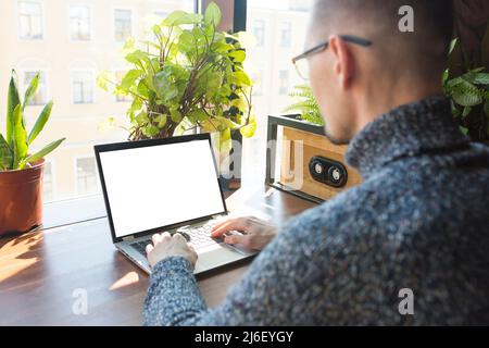 Mockup image of man using laptop with blank white desktop screen on wooden table. Stock Photo