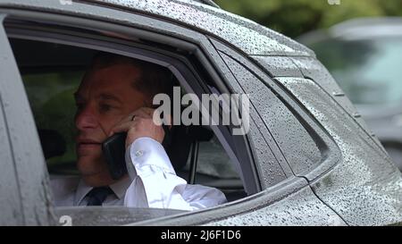 Businessman in the back of a car using a phone Stock Photo