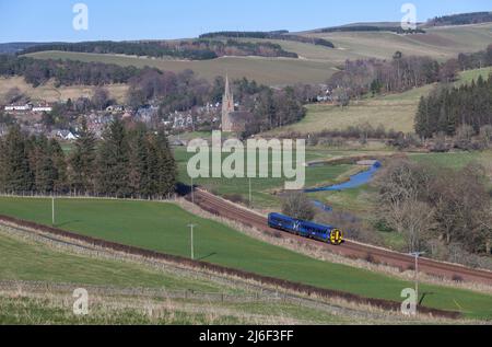 Scotrail class 156 DMU train 158728 passing the countryside and Stow St Mary of Wedale and Heriot church on the borders railway, Scotland UK Stock Photo