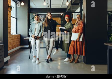 Successful designers smiling at the camera in an office boardroom. Multicultural businesswomen working as a team in an inclusive workplace. Group of c Stock Photo