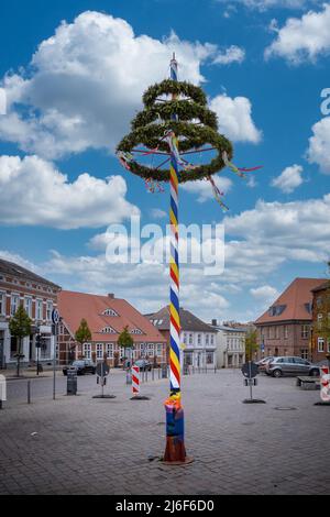 a colorfully decorated maypole stands on a marketplace Stock Photo