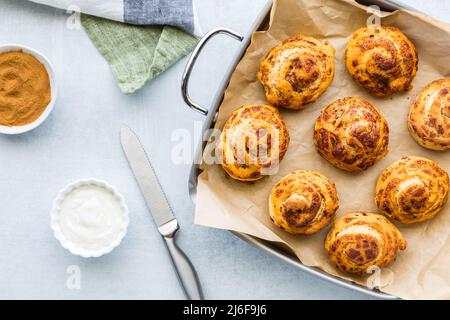 Top down view of a tray of freshly baked cinnamon rolls ready for frosting. Stock Photo