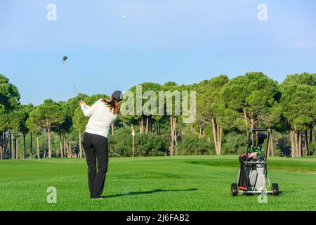 Female golf player hitting ball on fairway Stock Photo