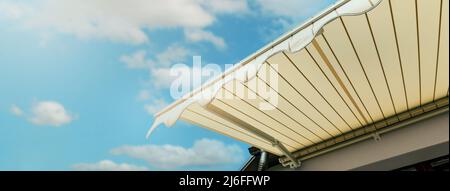retractable awning installed on wall over house window against blue sky. banner with copy space Stock Photo