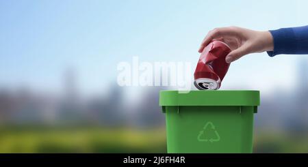 Woman putting a can in the trash bin, recycling concept, natural landscape in the background Stock Photo