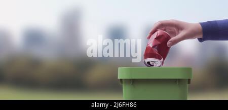 Woman putting a can in a garbage bin, recycling and waste sorting concept Stock Photo