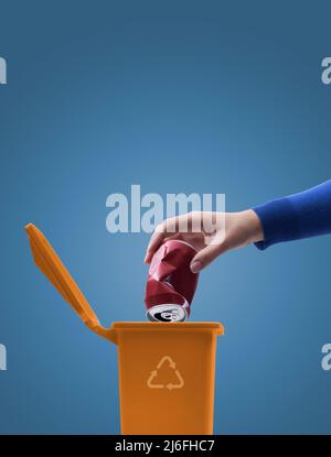 Woman putting a crushed can in the trash bin, separate waste collection and recycling concept Stock Photo