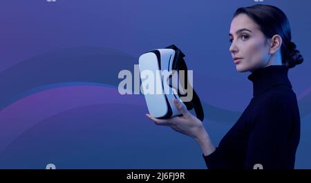 Young woman holding a VR headset and accessing virtual reality, abstract waves in the background, metaverse and immersive virtual reality concept Stock Photo