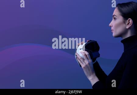 Young woman holding a VR headset and accessing virtual reality, abstract waves in the background, metaverse and immersive virtual reality concept Stock Photo