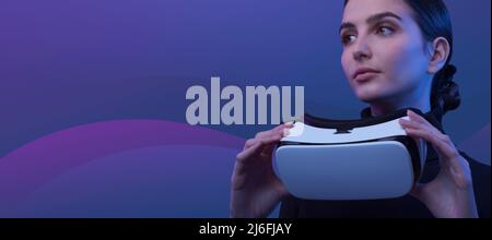 Young woman holding a VR headset and accessing virtual reality, abstract waves in the background, metaverse and immersive virtual reality concept Stock Photo