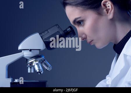 Young researcher looking through a microscope and checking samples, medical research concept Stock Photo