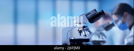 Professional laboratory microscope close up and scientists working in the background Stock Photo