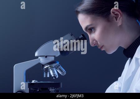Young researcher looking through a microscope and checking samples, medical research concept Stock Photo