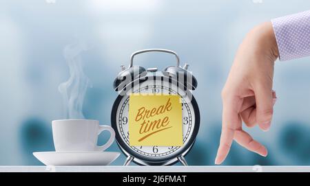Walking fingers going towards a cup of coffee and alarm clock with sticky note, it's break time Stock Photo