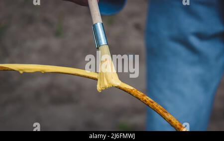 a man paints an iron frame with yellow and blue paint. selective focus Stock Photo