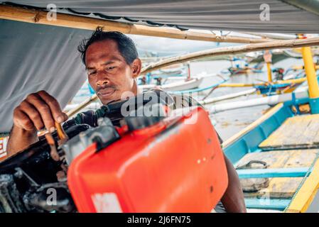 An Indonesian fisherman prepares his boat at the old fishers port near Perancak village, Bali, Indonesia Stock Photo