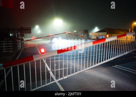 An automatic barriered level crossing in Barmouth, North Wales on a foggy night as the gates are operating Stock Photo